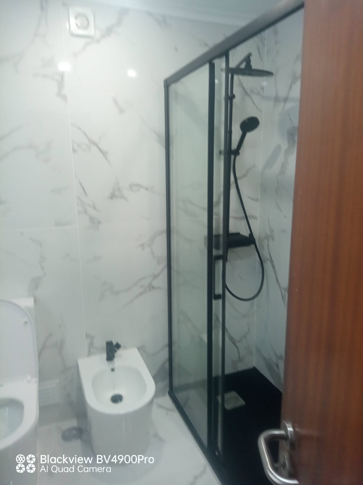 Duche com vidro preto e parede em mármore branco